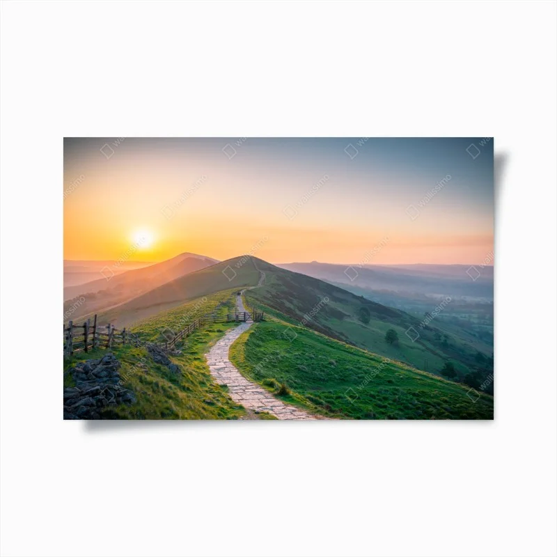 Plakat wschód słońca nad zielonymi wzgórzami z kamienną ścieżką