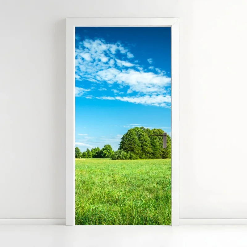 Naklejka na drzwi słoneczna zielona łąka pod niebieskim niebem