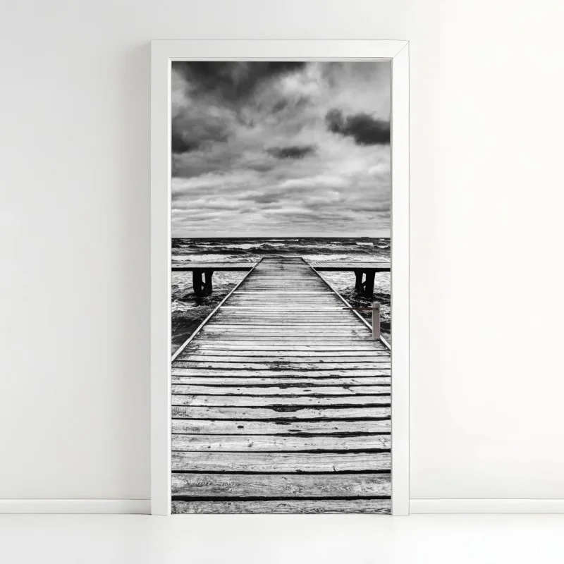 Naklejka na drzwi dramatyczne czarno-białe molo prowadzące w burzliwe morze