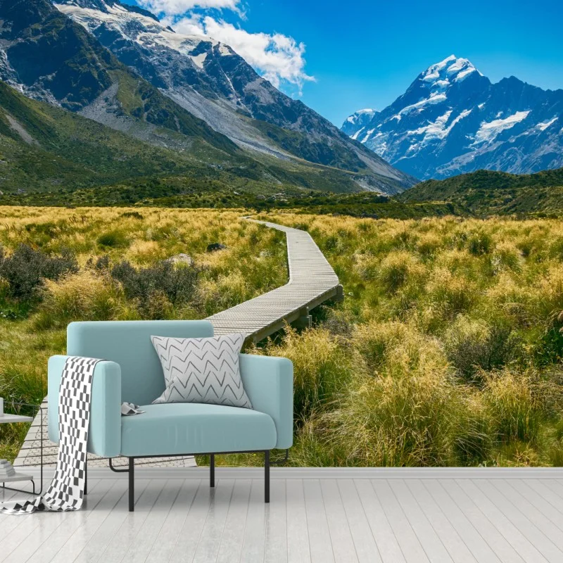 Fototapeta kładka przez łąkę prowadząca do ośnieżonych szczytów