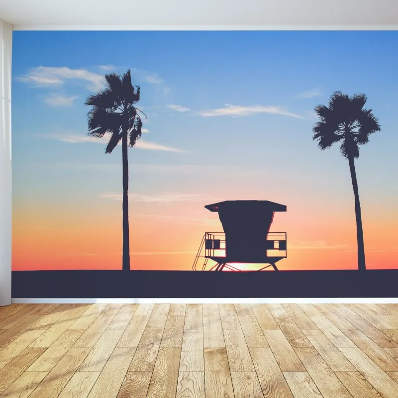 Fototapeta zachód słońca nad plażą z sylwetką wieży ratownika