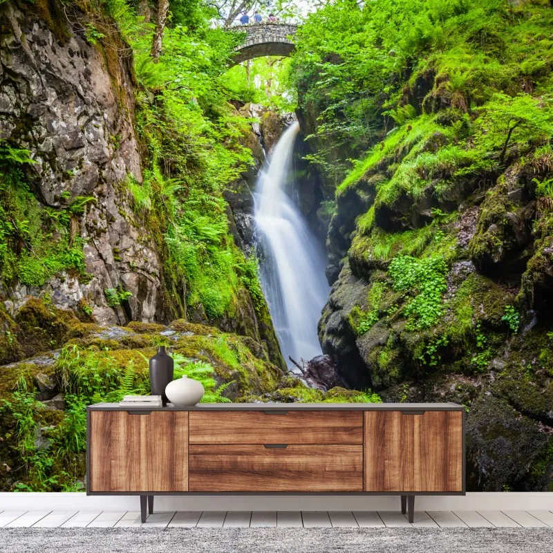 Fototapeta wodospad w mchem porośniętym wąwozie z kamiennym mostem