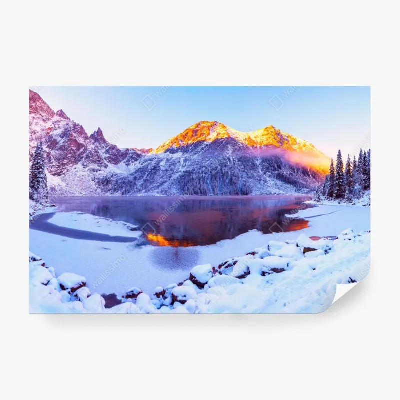 Wall mural sunlit mountains over frozen alpine lake
